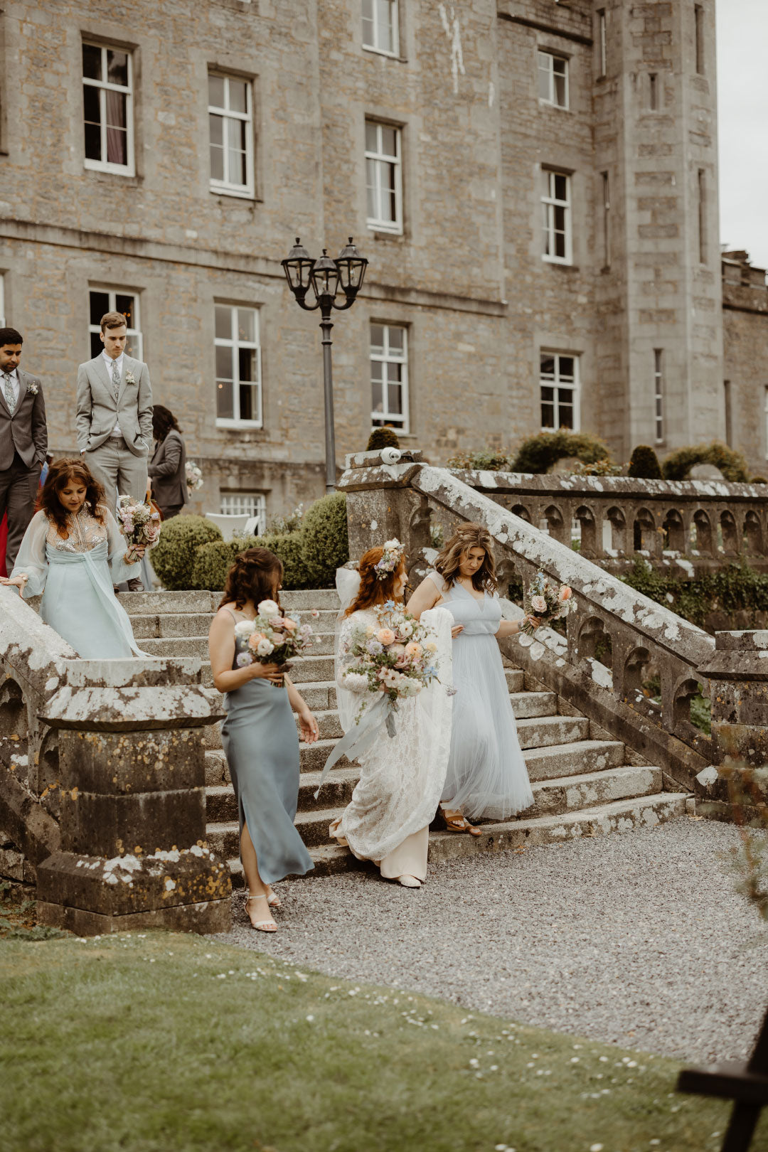 Bride with Bridesmaids walking down stairs of wedding venue
