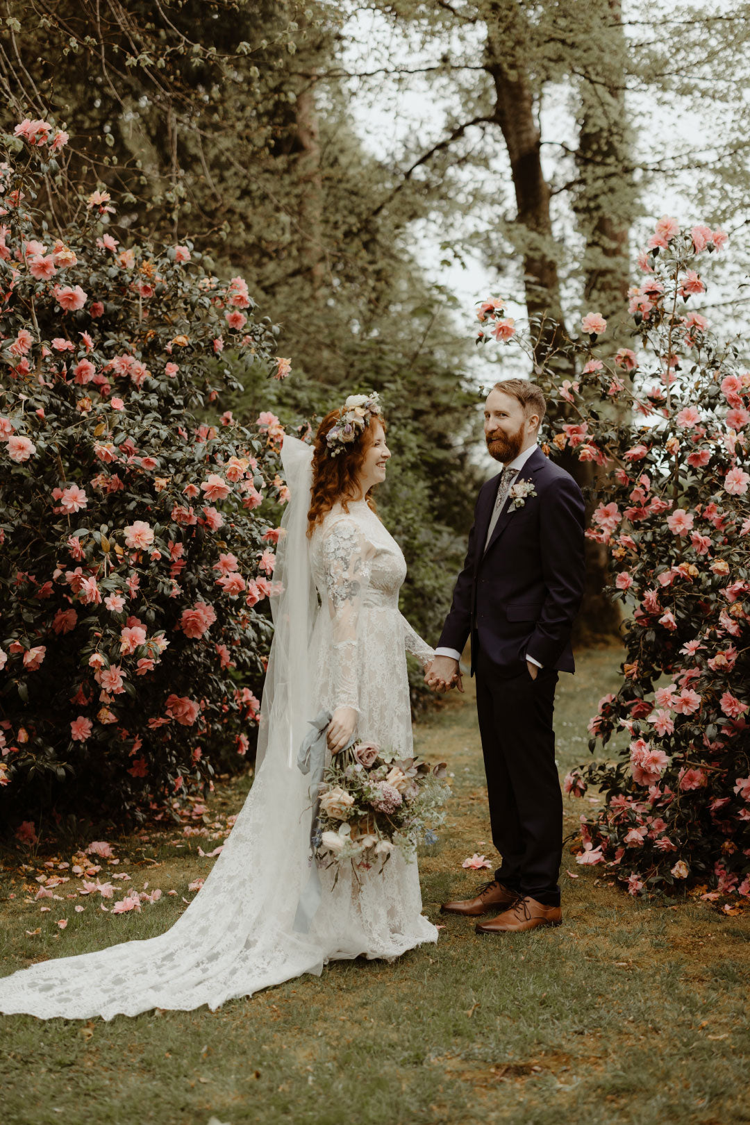 Bride and Groom posing next to garden roses Bride in Beverly Custom Wedding Dress