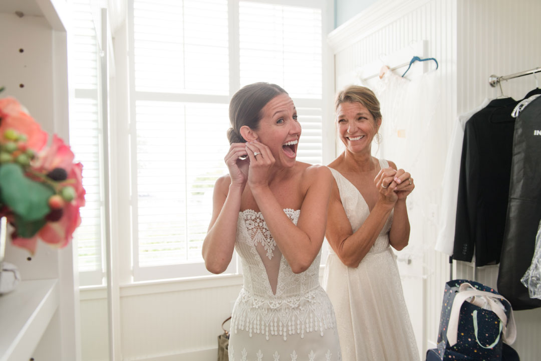 Bride putting on earrings before wedding with mother of the bride