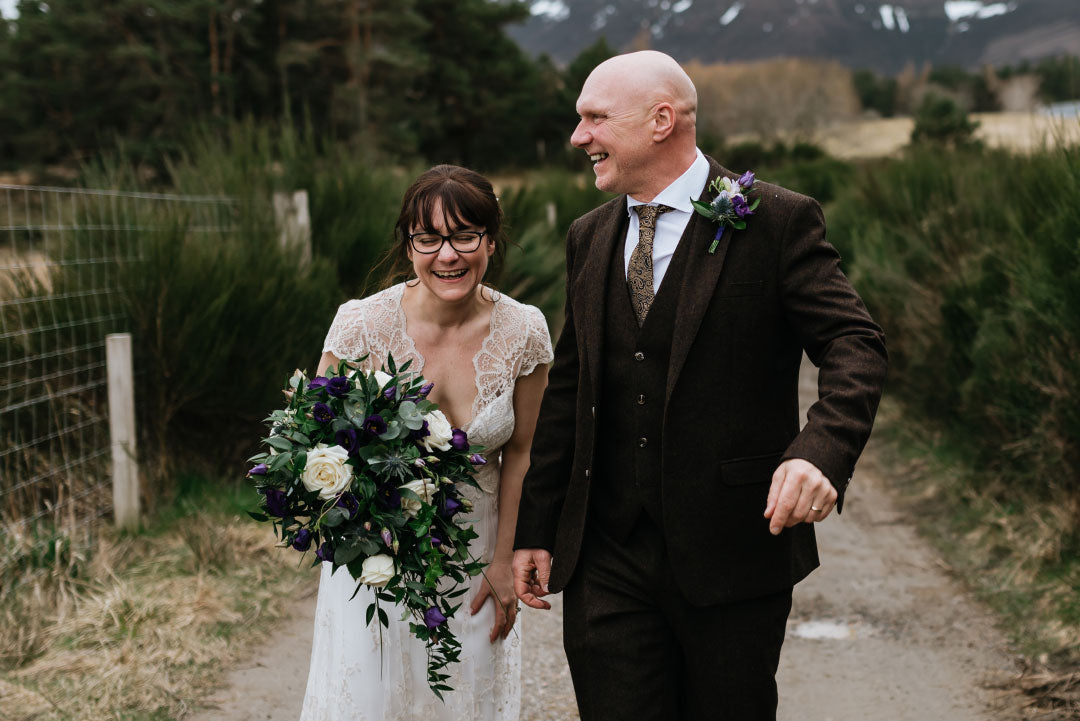 Bride with groom walk on dusty path