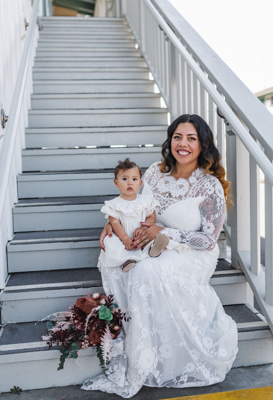 Bride wearing Claire Pettibone wedding dress holding baby