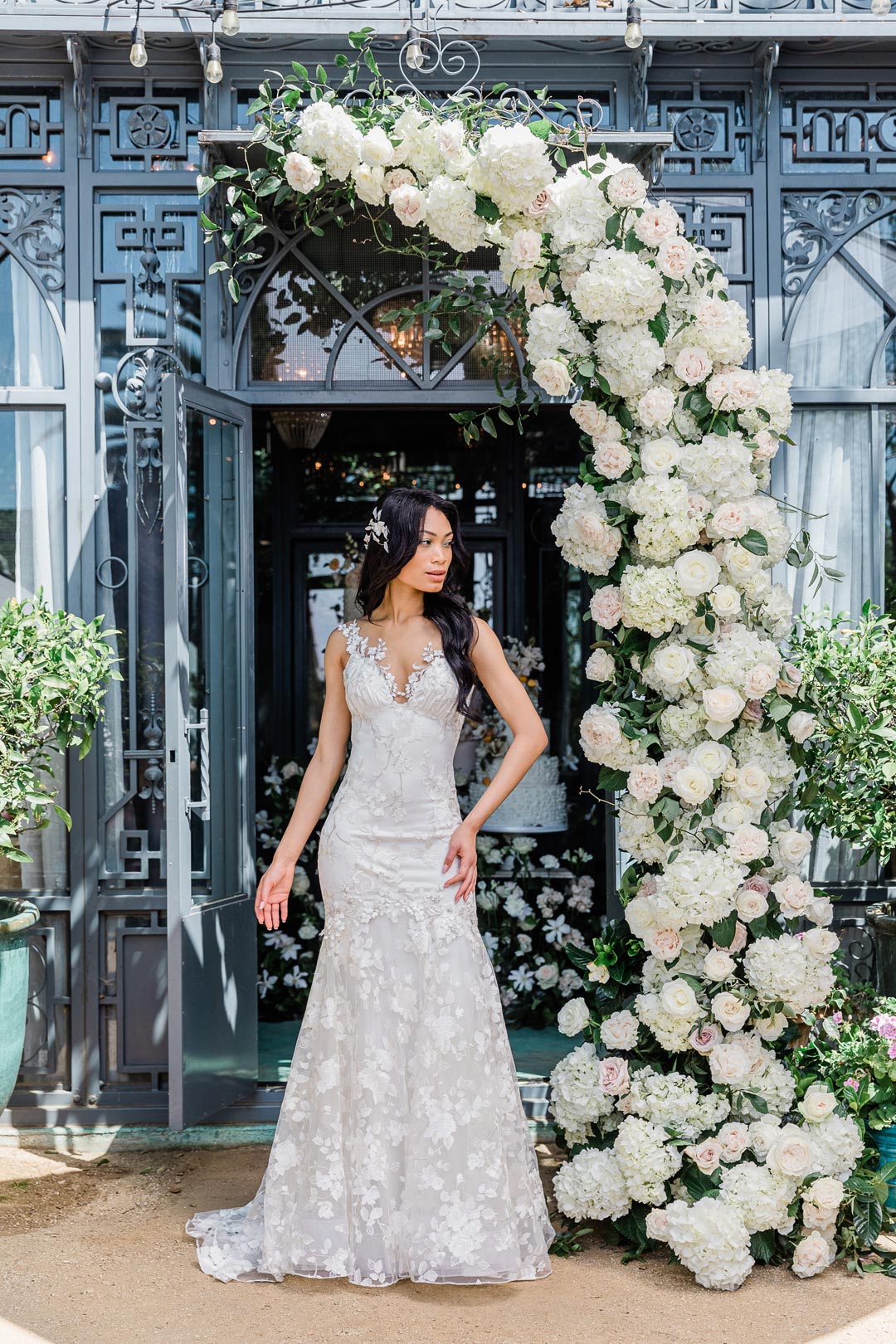 April Ivory Wedding Dress Model in front of Wedding Floral Arrangement