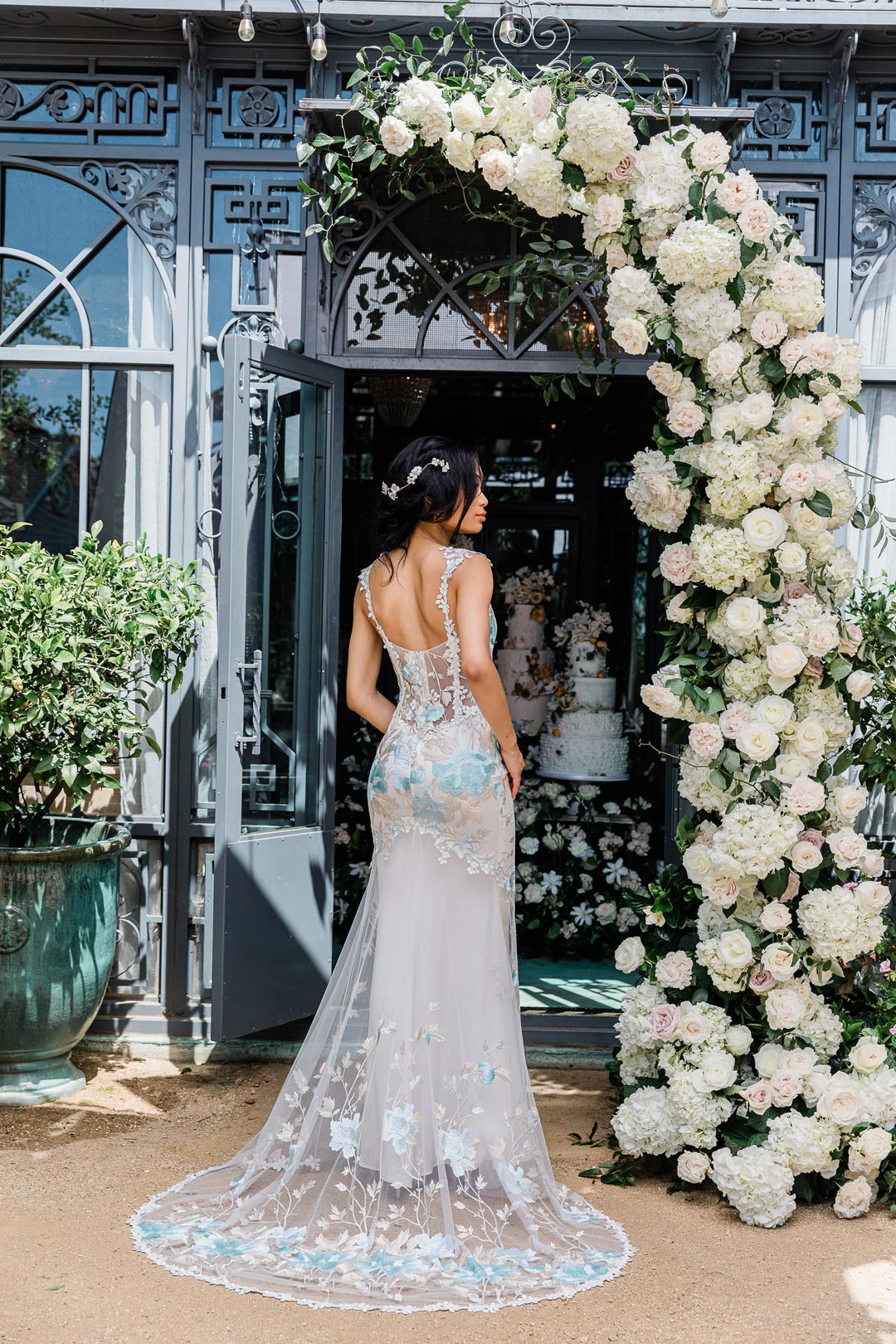 Wedding Dress Odessa Blue in front of Floral Archway