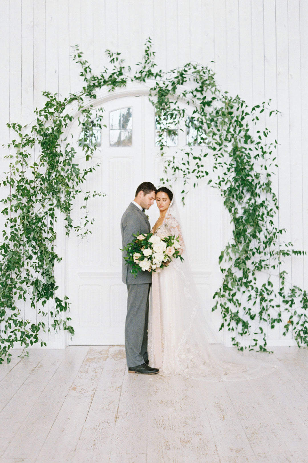 Bride and groom at floral and greenery arch