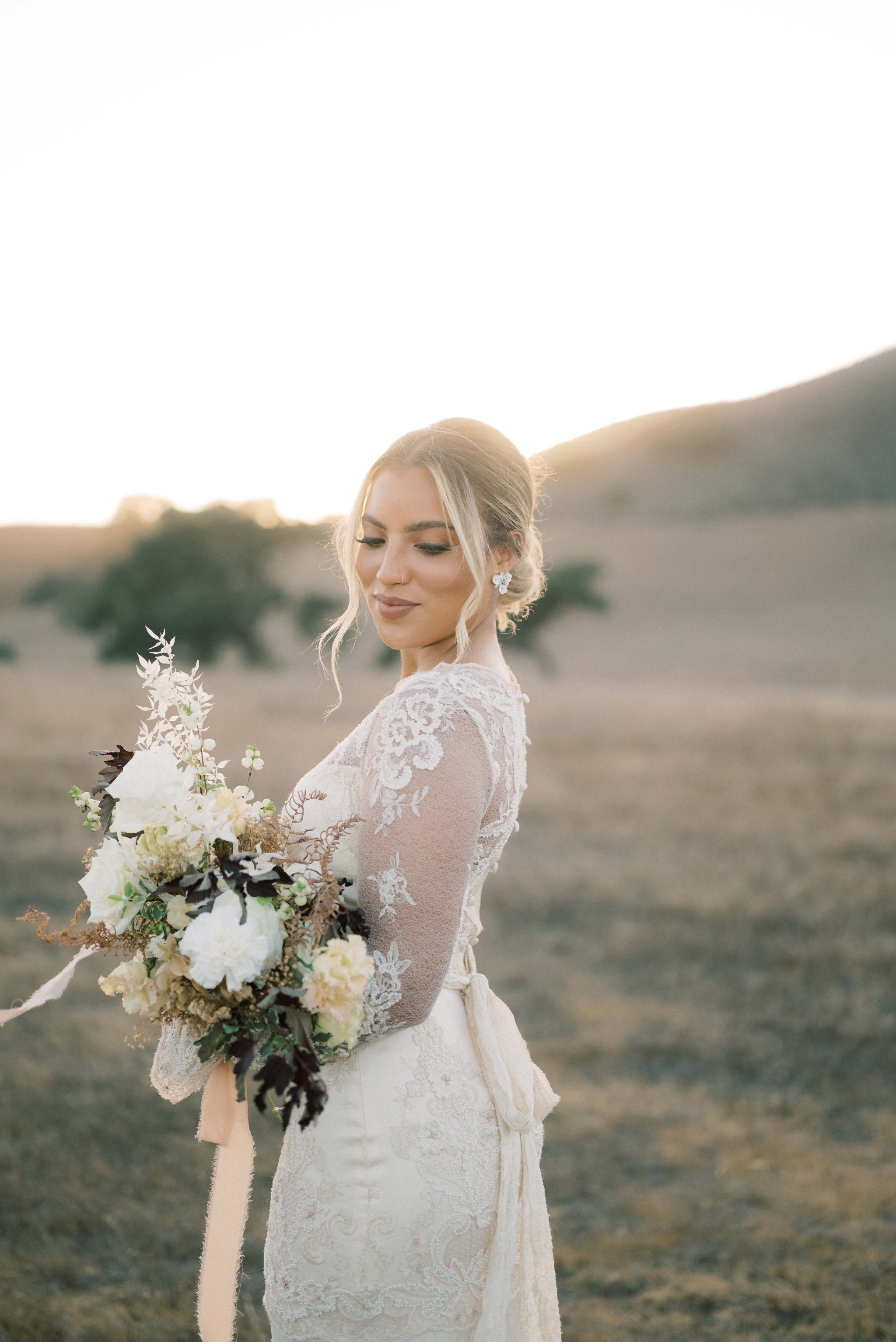 Bride holding wedding flowers in open field