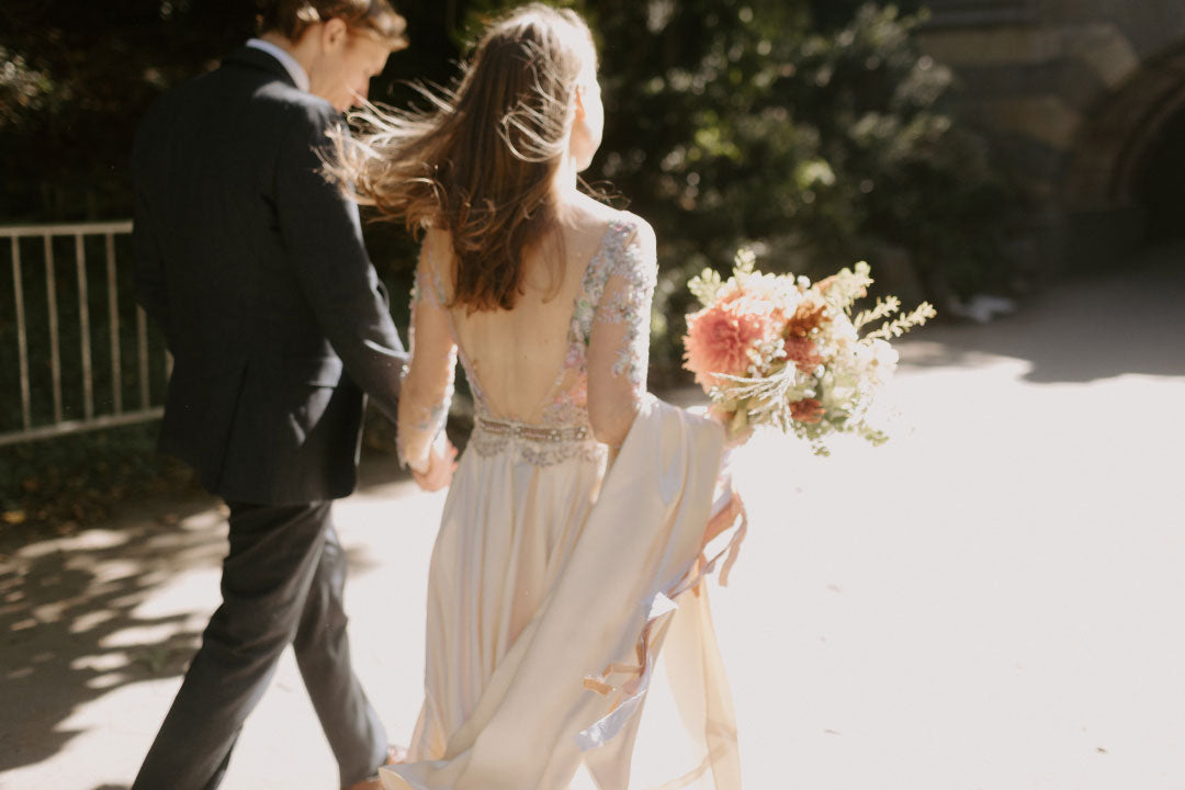 Bride and groom walking Bride holds silk wedding dress skirt