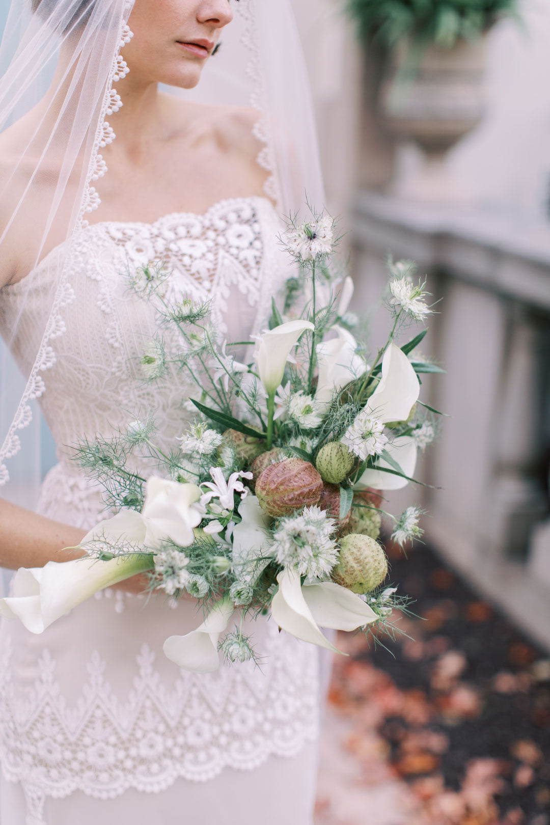 Wedding dress lace and embroidery detail bride holding a floral boquet