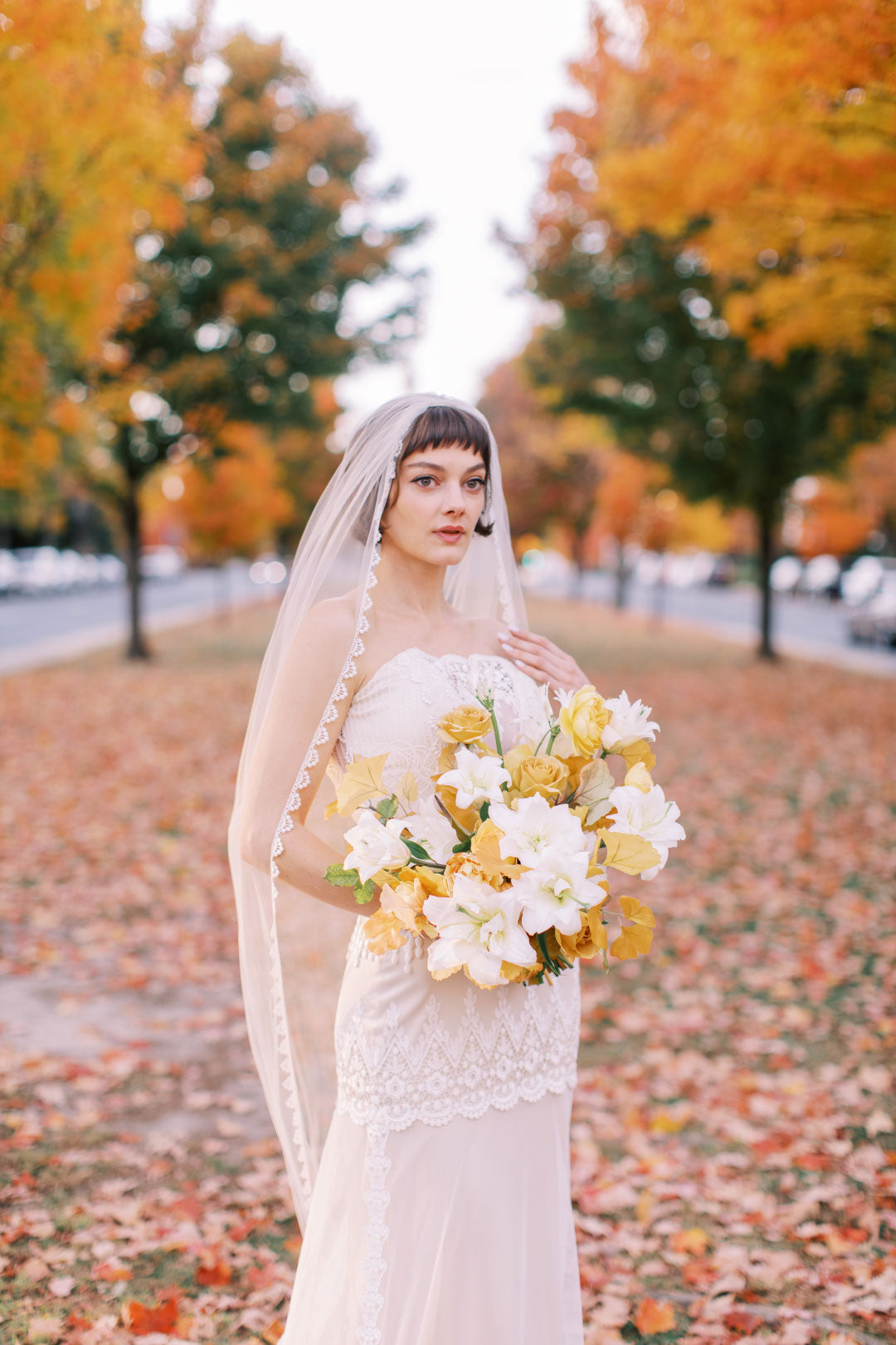 Bride holding wedding floral boquet with fall leaves