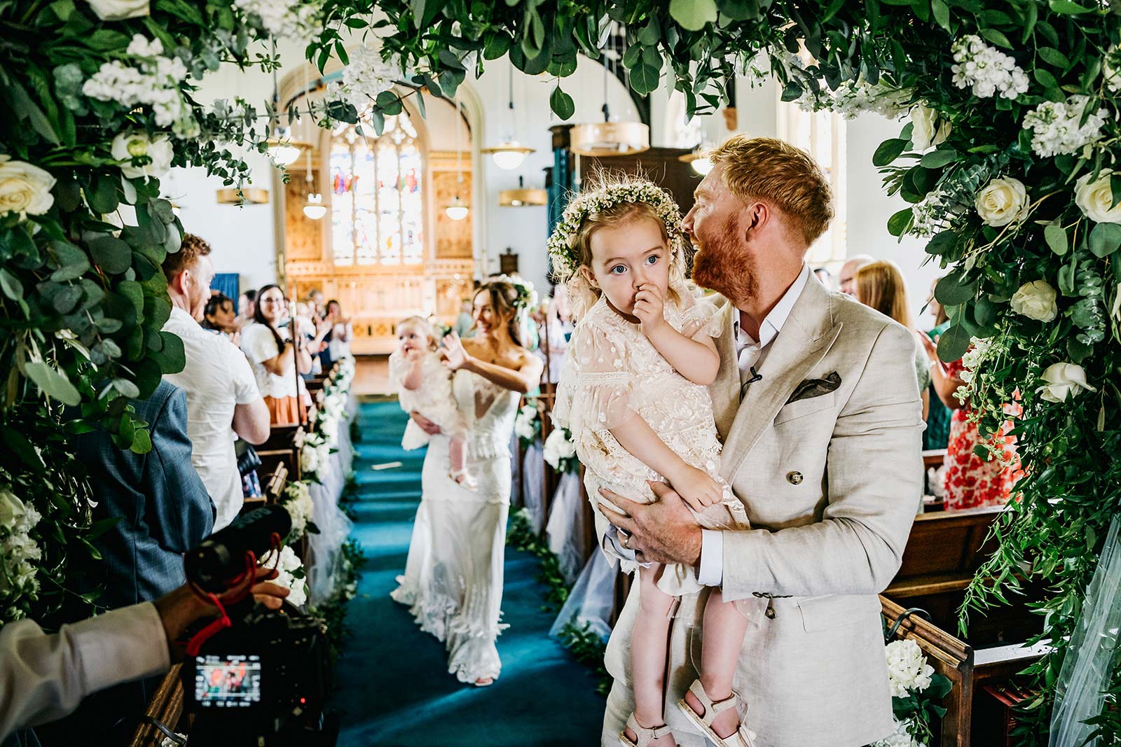 Groom and Bride leaving wedding chapel with babies in arms