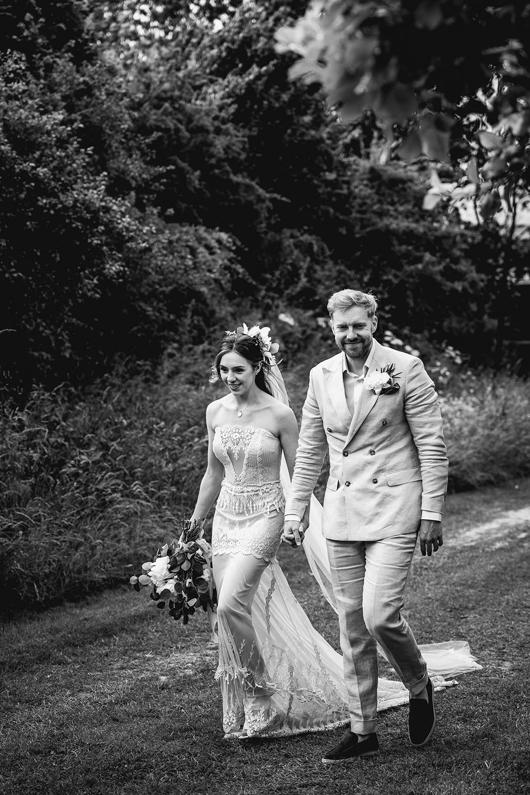 Black and white photo of bride and groom walking after wedding ceremony