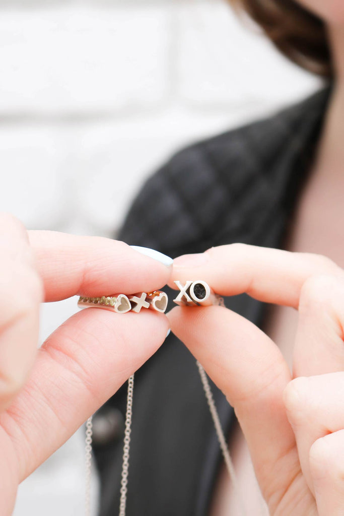 Custom BFF geomstone necklaces being held up by two female friends