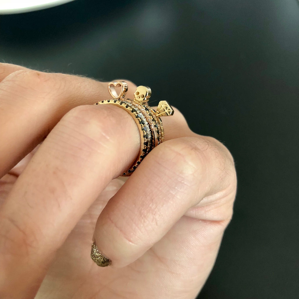 A stack of rings on a hand featuring shapes like skull and diamond