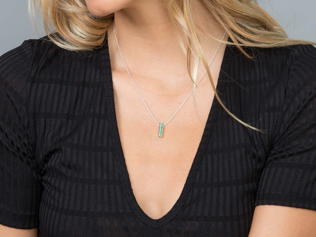 A girl wears a Heart pendant set with emeralds