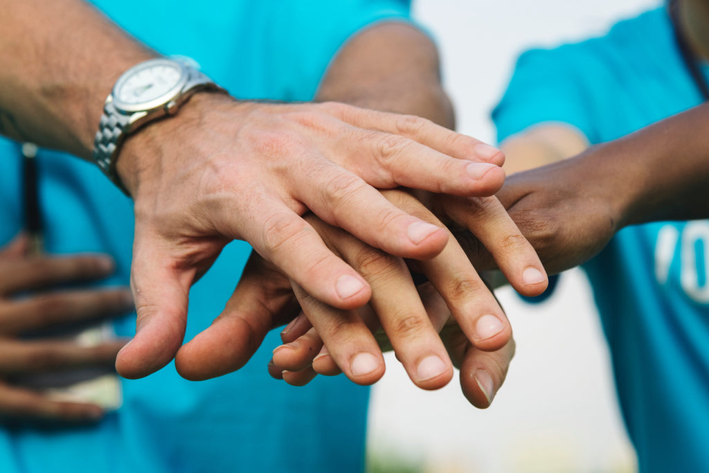 a group of people put their hands in to celebrate completing a good deed