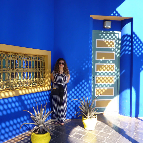 Blue and yellow architecture in Marjorelle Gardens, with woman in patterned shadows