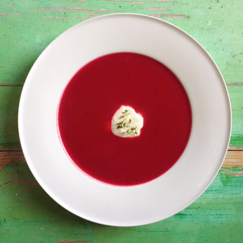 Beetroot soup with sour cream and herbs on green table