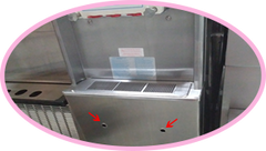 taylor soft serve frozen yogurt machine front panel under drip tray has red arrows pointing at holes where you can press the breaker reset button