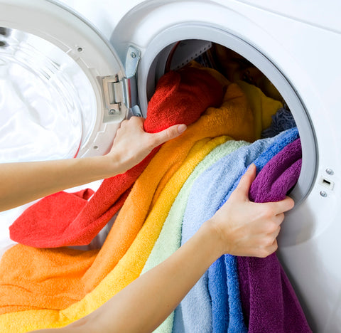 Laundry beign loaded into a washing machine