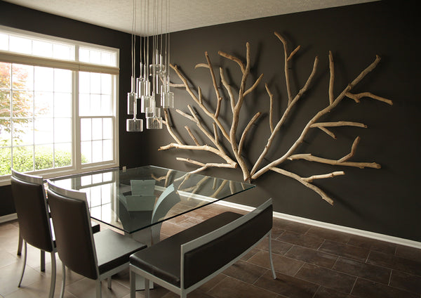 A driftwood wall art installation by Susie Frazier feels like sprawling tree branches on an interior wall.