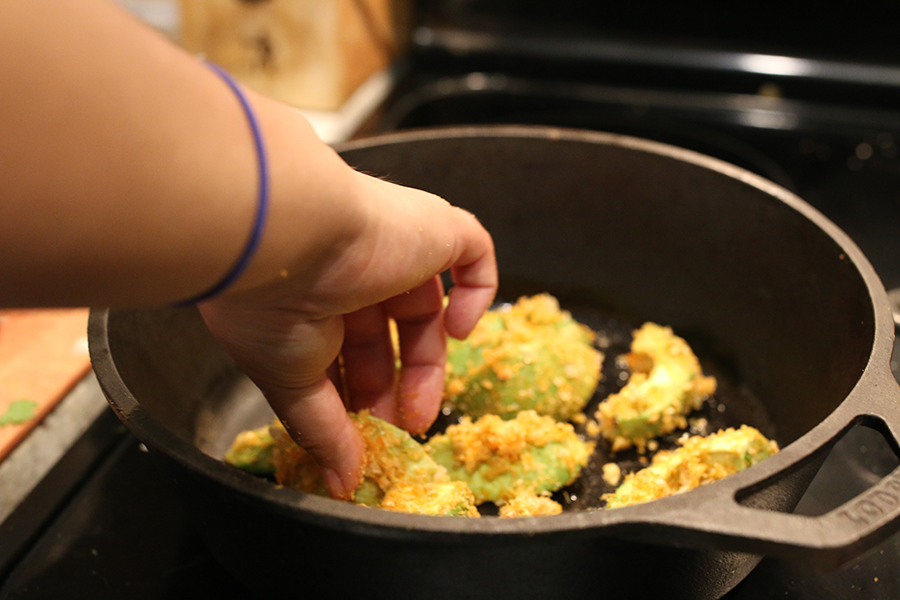Breaded avocado cooking in a skillet.