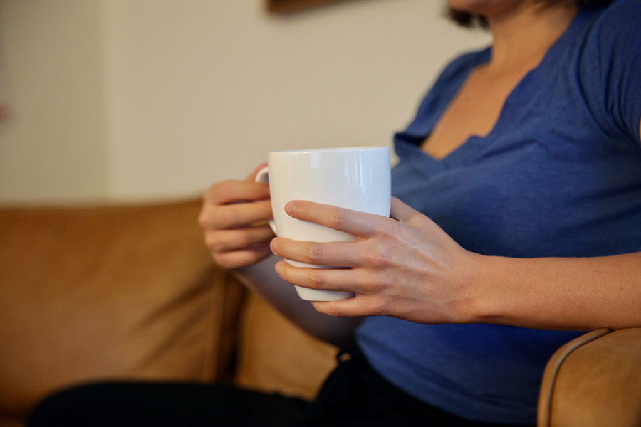 Woman sitting on couch holding a cup of coffee.