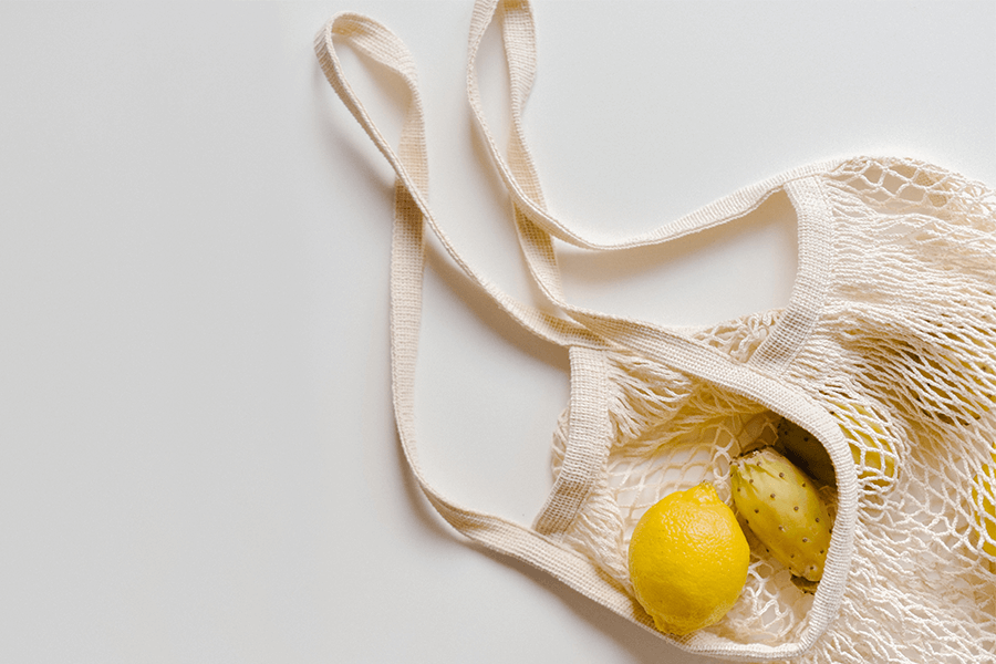 Mesh bag with fruit on white background 
