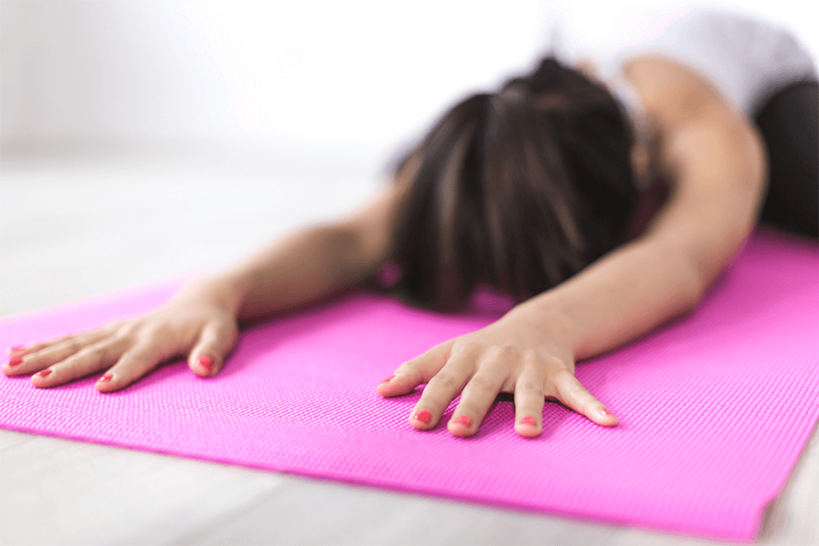 Woman stretching out on pink yoga mat