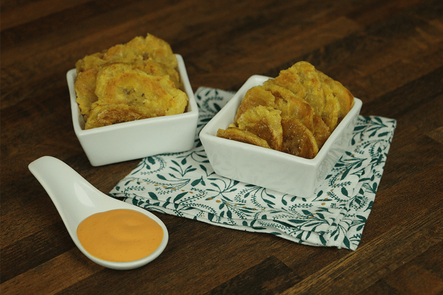 Fried plantains in white ramekins with orange dipping sauce 