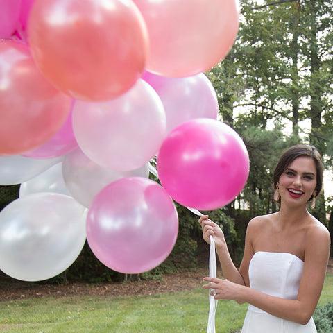 close up of beautiful bride in a strapless white casual short wedding dress and pink balloons