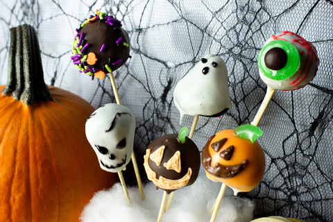 Spooky Cake Pops in the shape of an eyeball, pumpkins, a ghost, a skull, and decorated with sprinkles