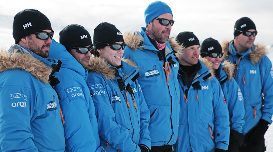 A group of men and women standing in a line wearing the same style arctic parka in a sky blue color