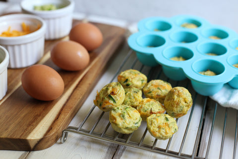 Egg and broccoli fritters with silicone freeze tray in the back also eggs and ramekins 