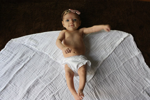 Baby laying on a organic cotton swaddle blanket