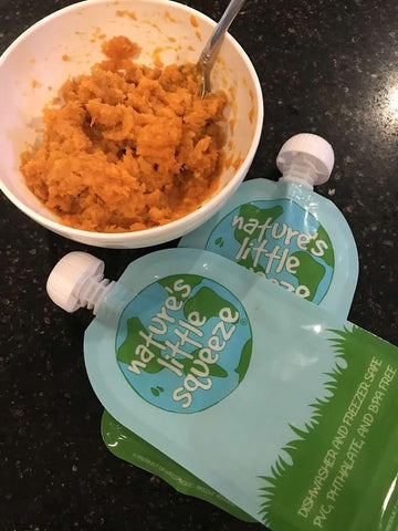 Orange food in a bowl with 2 reusable food pouches next to it