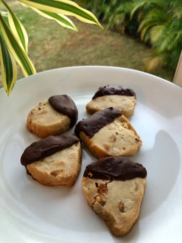 mac nut shortbread cookies dipped in chocolate on white plate