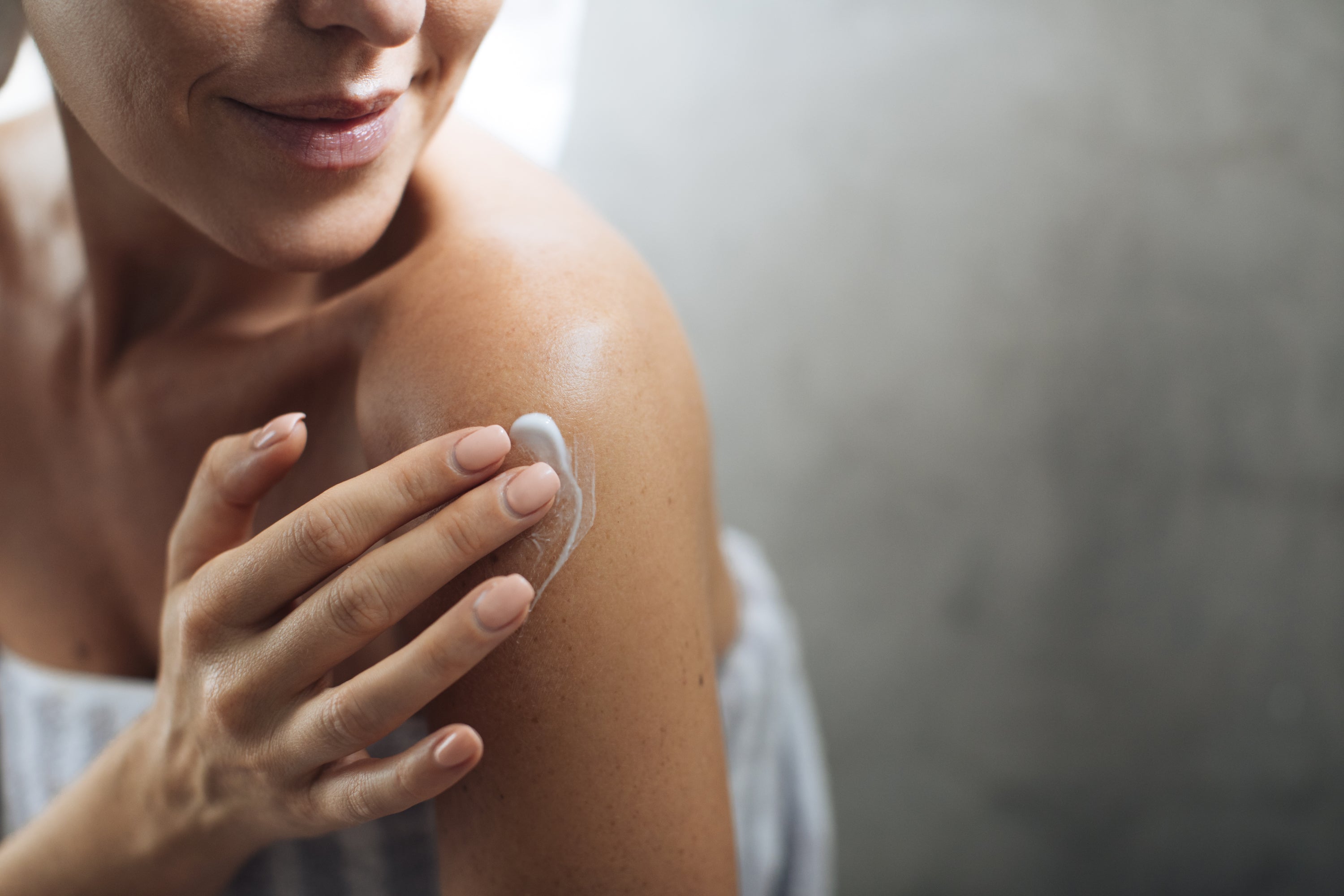 woman applying lotion to shoulder