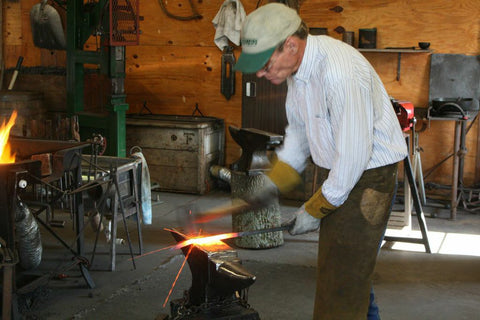 Walter is hammering out the red hot iron to begin forming a leaf.