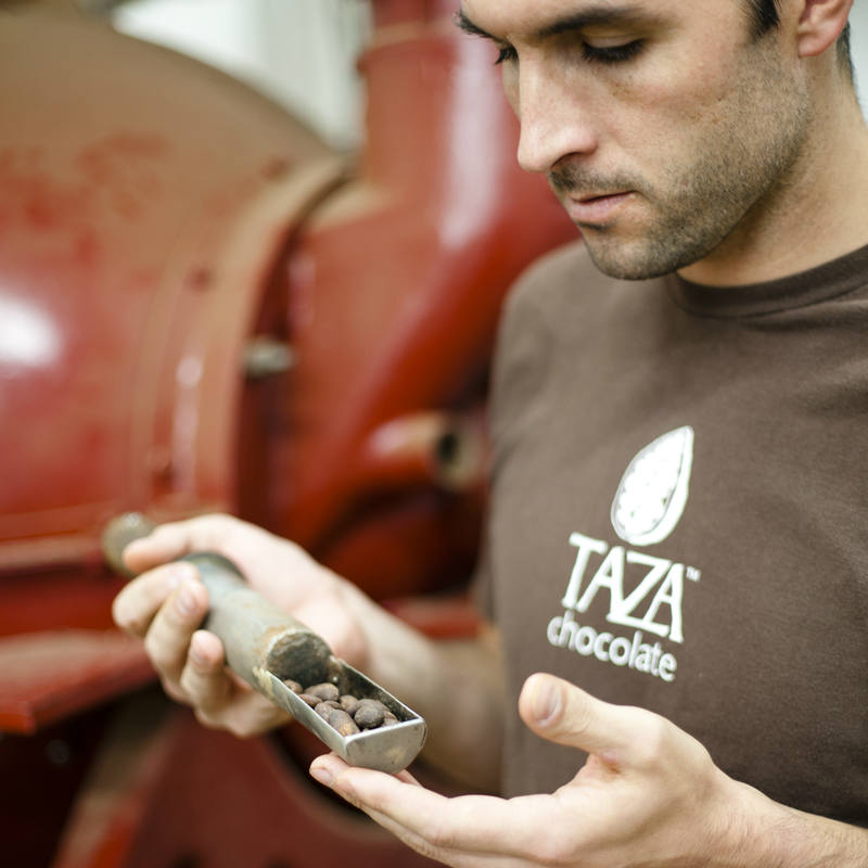 Taza Chocolate founder, Alex Whitmore, checking cacao beans during a roast