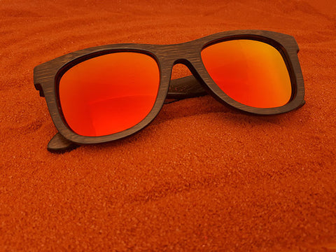 Occhiali da sole in legno Okulars Sunlight su sabbia colorata rossa