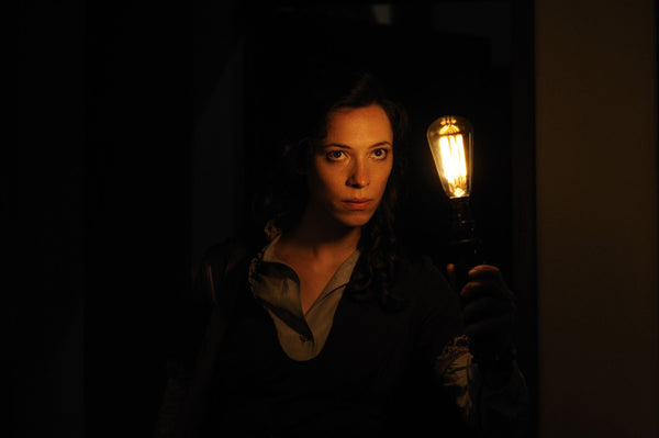young woman holding a lantern in a dark room