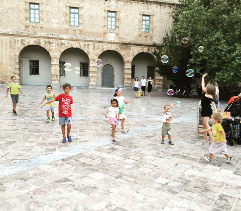 Children chasing bubbles at main square Nafplio, Greece. Travel, children, love, travel with children