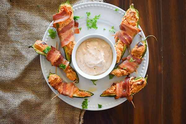 Jalapeno Poppers on a plate stuffed with cream cheese seasoned with Chugwater Chili Dip & Dressing Mix and Wrapped in bacon