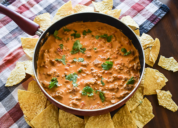 Beefy cheese queso in skillet with tortilla chips