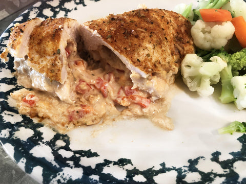 up close image of cooked stuffed chicken on plate with veggies