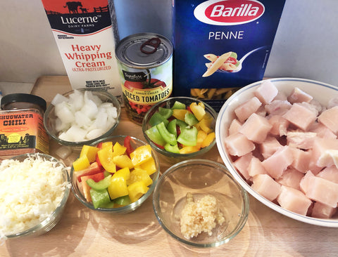 Up Close of fajita pasta ingredients, peppers, onion, tomatoes, chicken, garlic, cheese, chili seasoning, cream, pasta