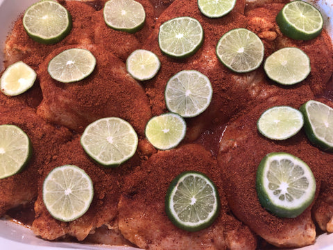 up close image of chicken breasts with chili seasoning and limes 