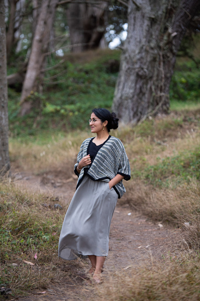 Manpreet Kalra wearing a flowey grey midi skirt and a hand-woven black and grey cardigan