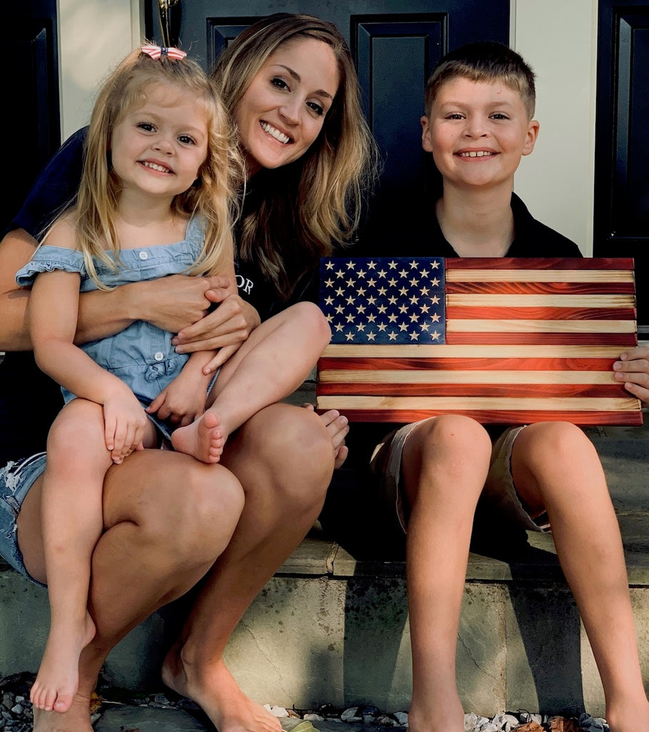 Lauren and her happy kids holding a wood American flag