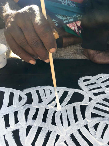 Aboriginal artist Betty Mbitjana painting with paint brush