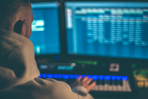 Music producer in front of the computer screen with a midi keyboard